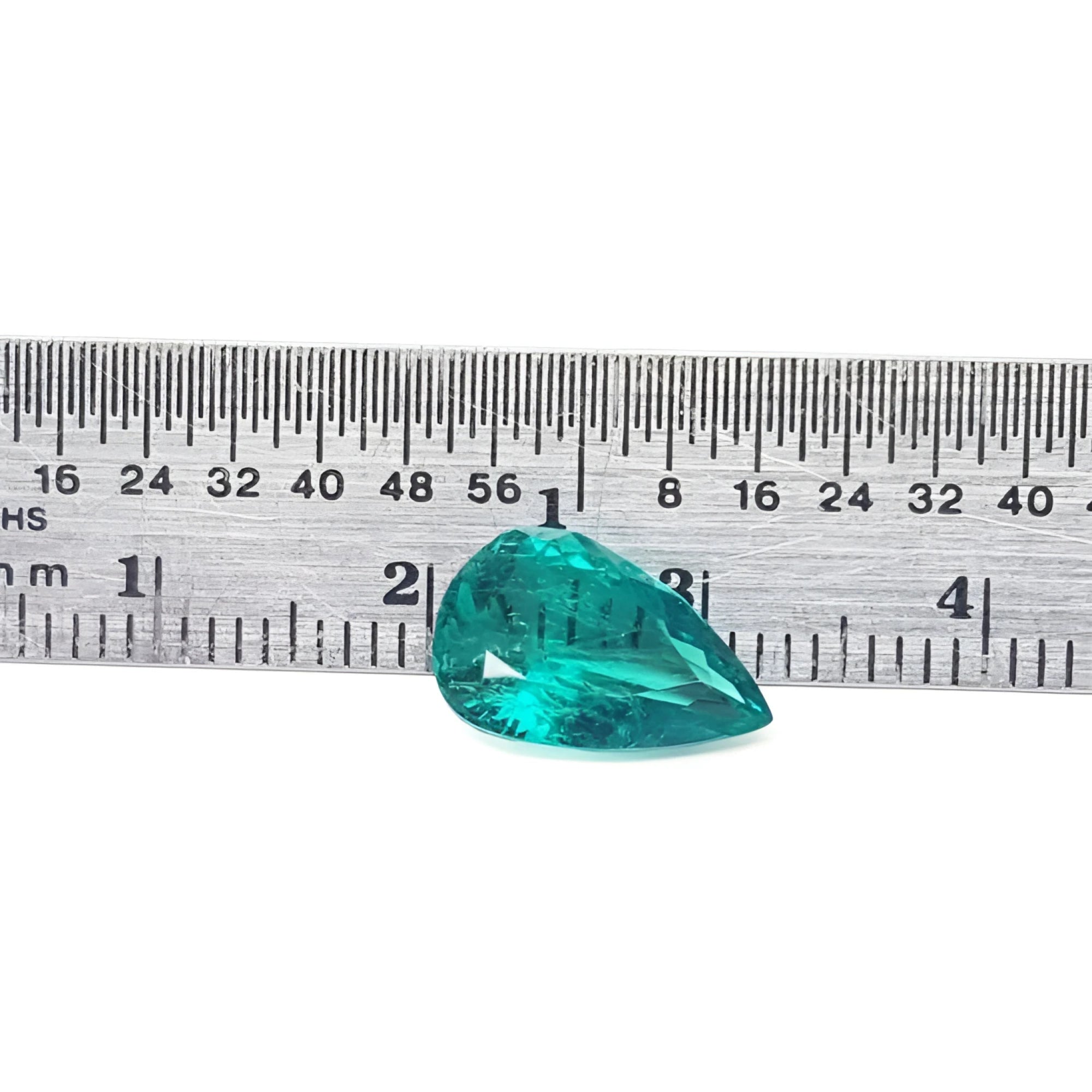 2.65 carat pear cut loose Colombian emerald with vibrant medium deep green hue next to a ruler.