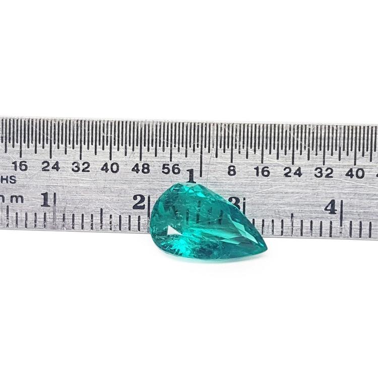 2.65 carat pear cut loose Colombian emerald with vibrant medium deep green hue next to a ruler.