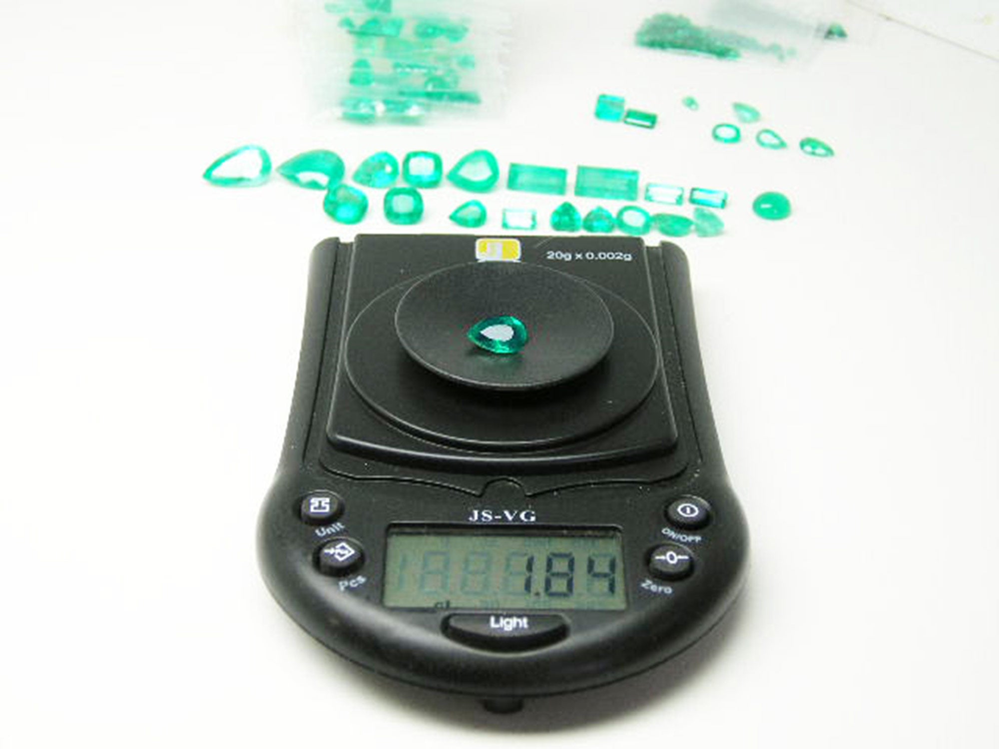 Pear cut natural colombian emerald muzo mine, on electronic scale for weight view