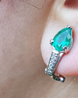 Close-up of a teardrop emerald earring clip-on system on an ear.
