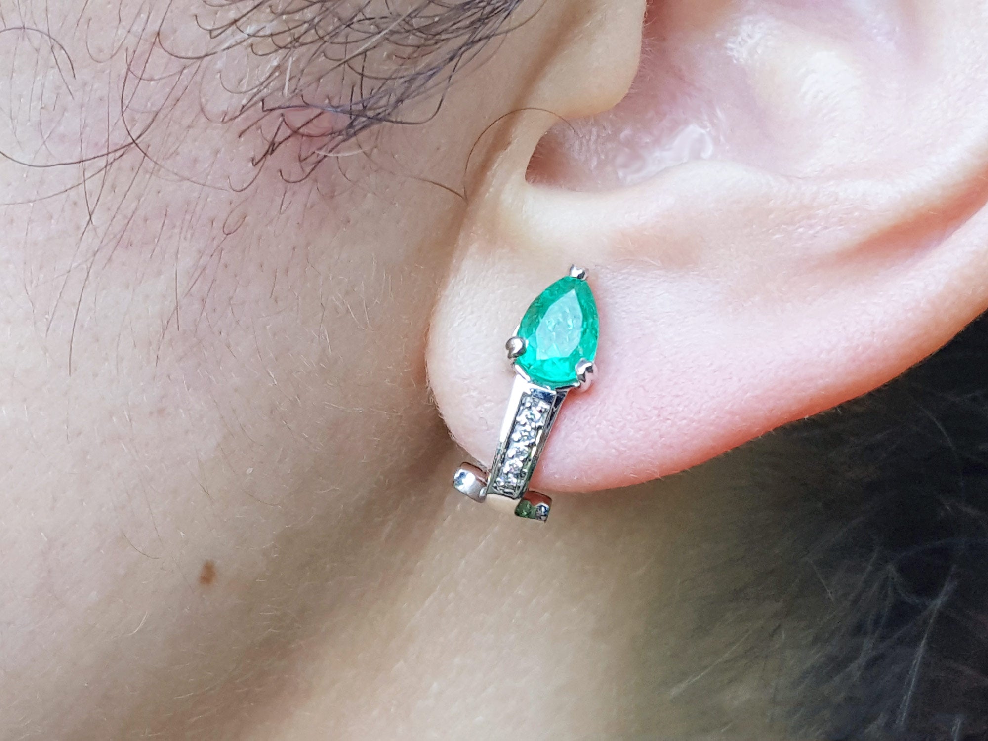 Close-up of an ear wearing gift for Mother&#39;s Day emerald clip on earring.