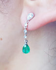 Close-up of an emerald teardrop earring on a person's ear.
