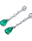 Pair of emerald teardrop and diamond earrings on a left side position top view