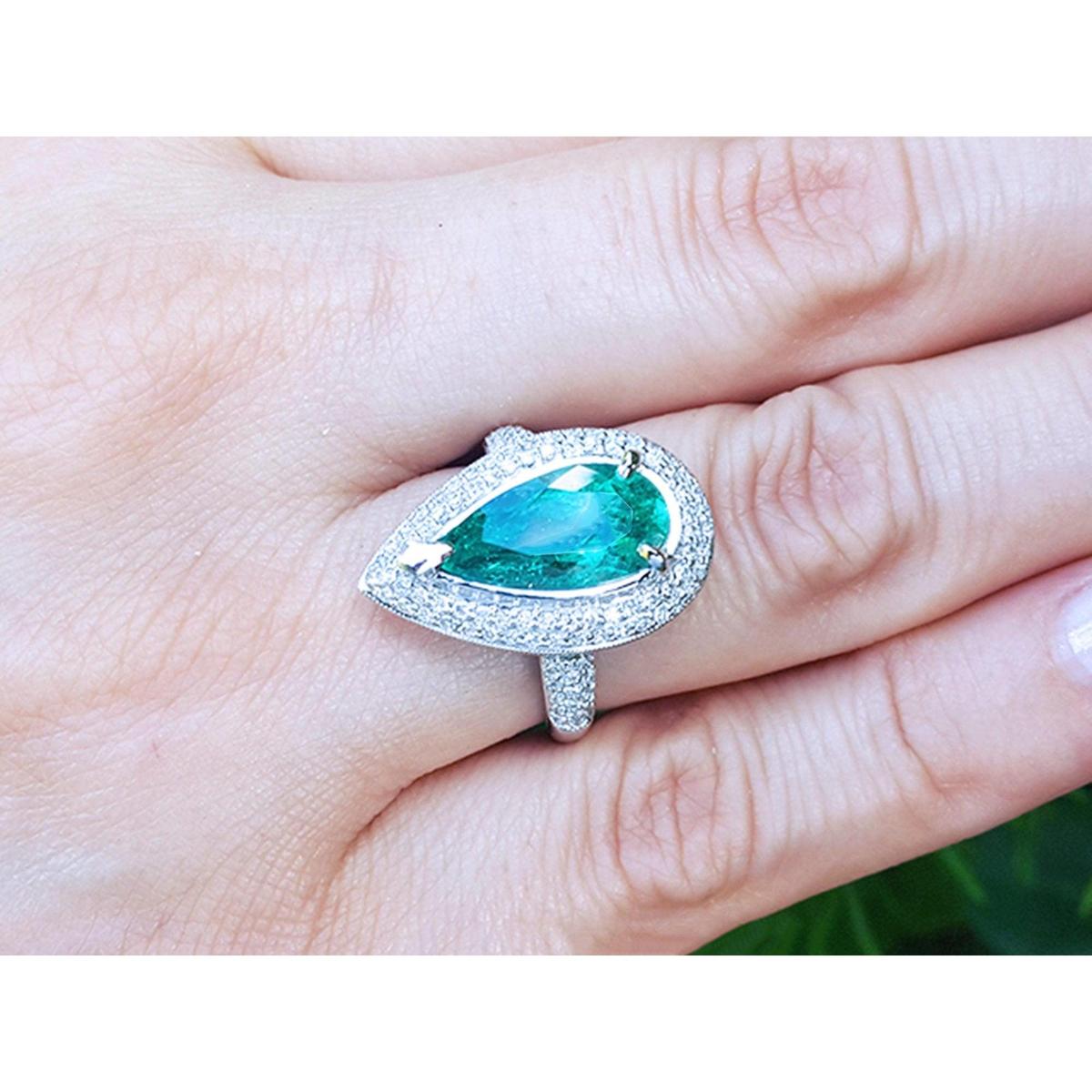 A USA made women’s emerald ring pear shaped, between a woman's fingers.