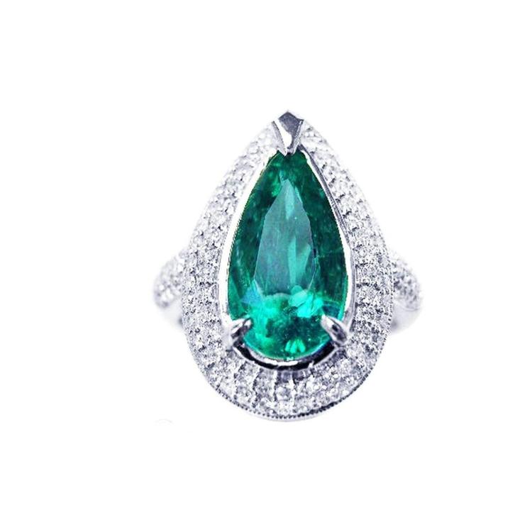An emerald ring, pear shaped held by three prong set, encircled by double halo diamond, in 14k white gold.