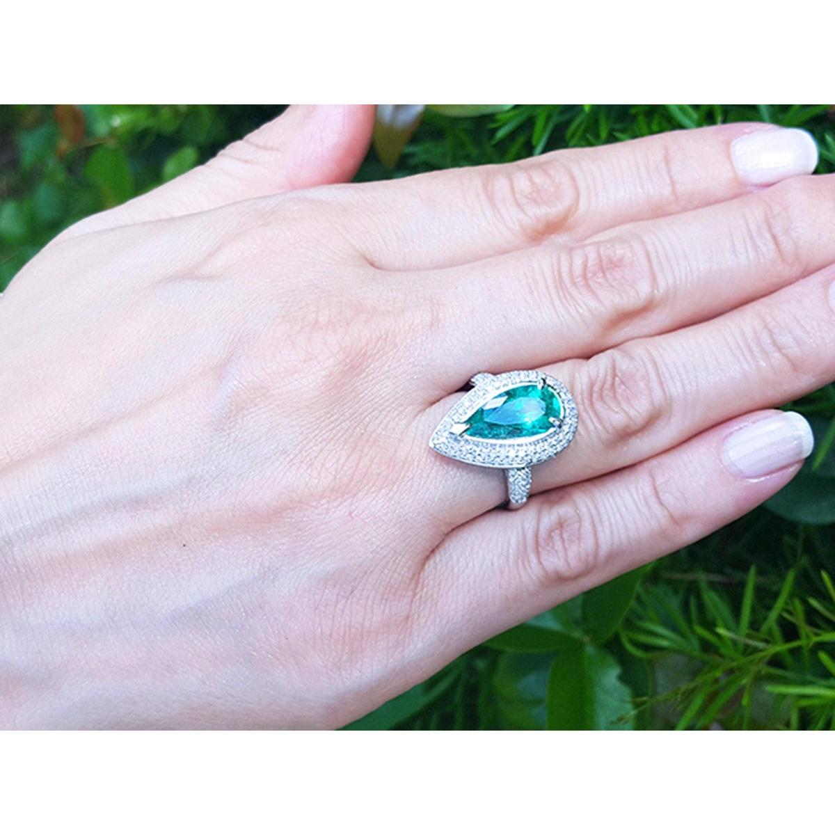 Hand wearing a real Colombian emerald ring for women against a natural background.