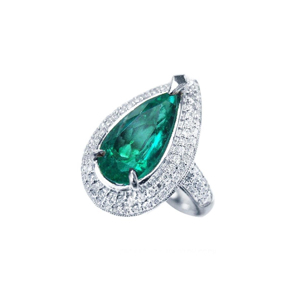 An emerald ring, pear shaped green gemstone encircled by double halo diamond, top and right side profile view.