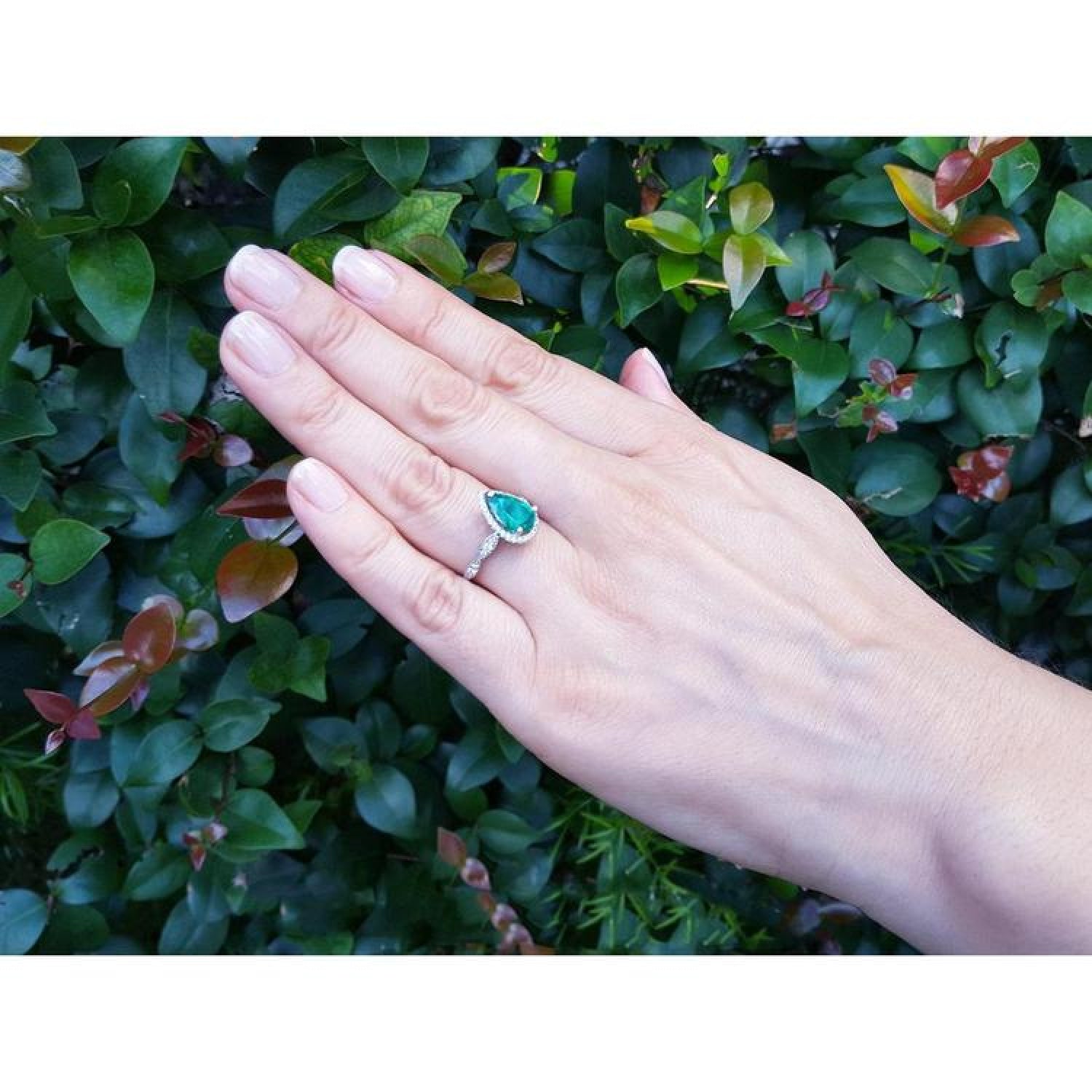 1.43 ct teardrop emerald engagement ring in 14K white gold with diamond halo on a hand.