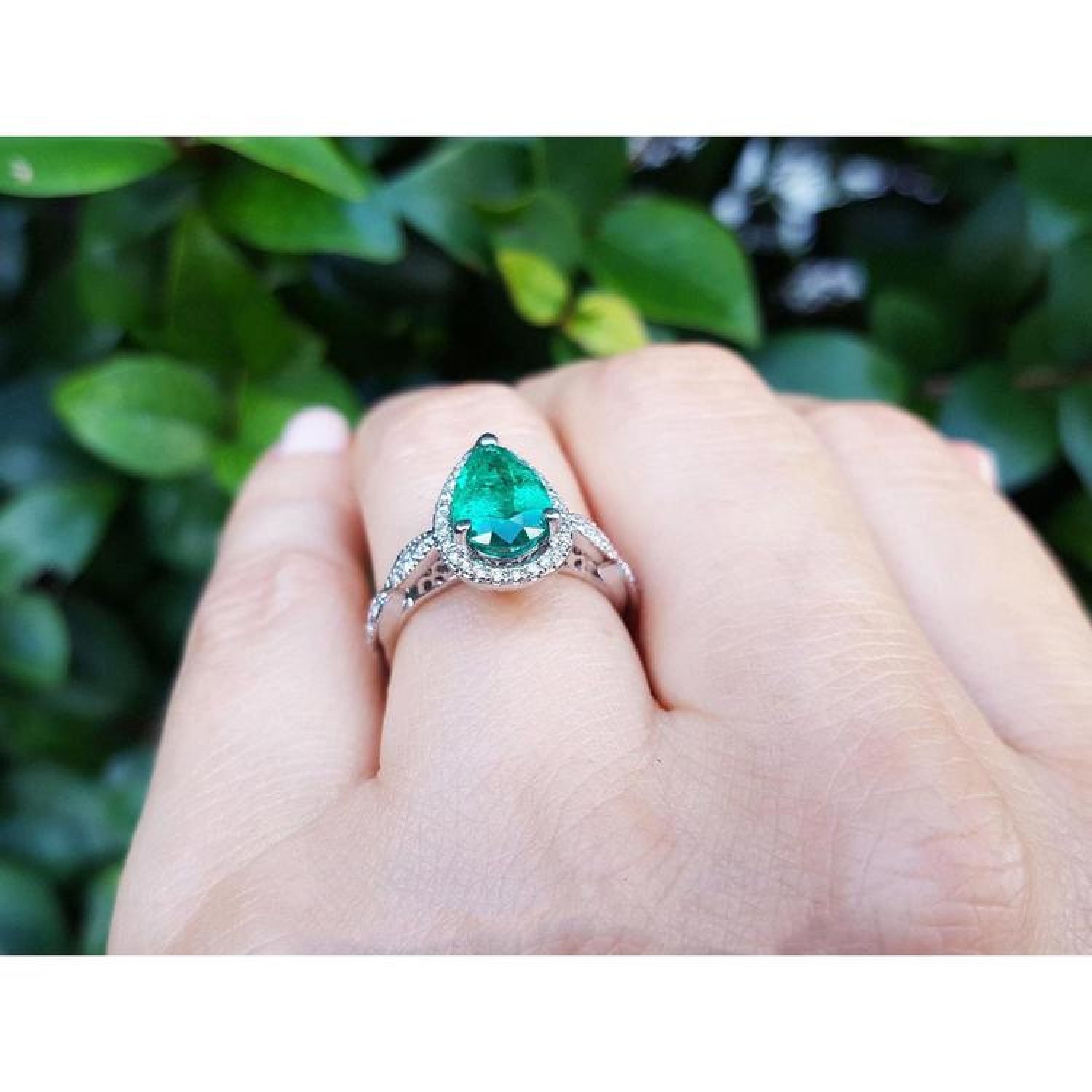 1.43 ct teardrop emerald engagement ring in 14K white gold with diamond halo on a hand.