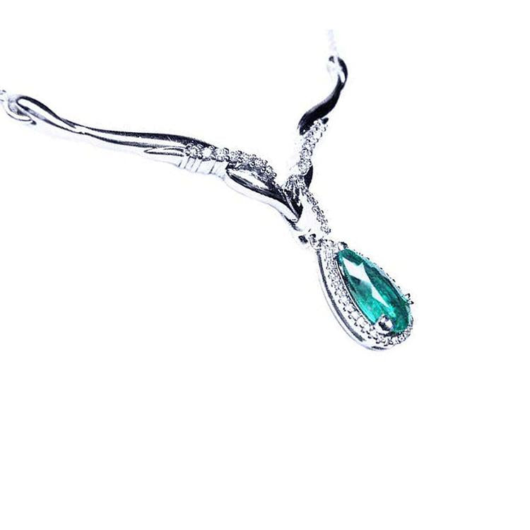 A 14k white gold women's emerald necklace pear cut encircled by a halo natural diamond.
