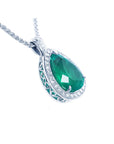 Pear-shaped emerald pendant with diamond halo and intricate 14K white gold setting on a chain.