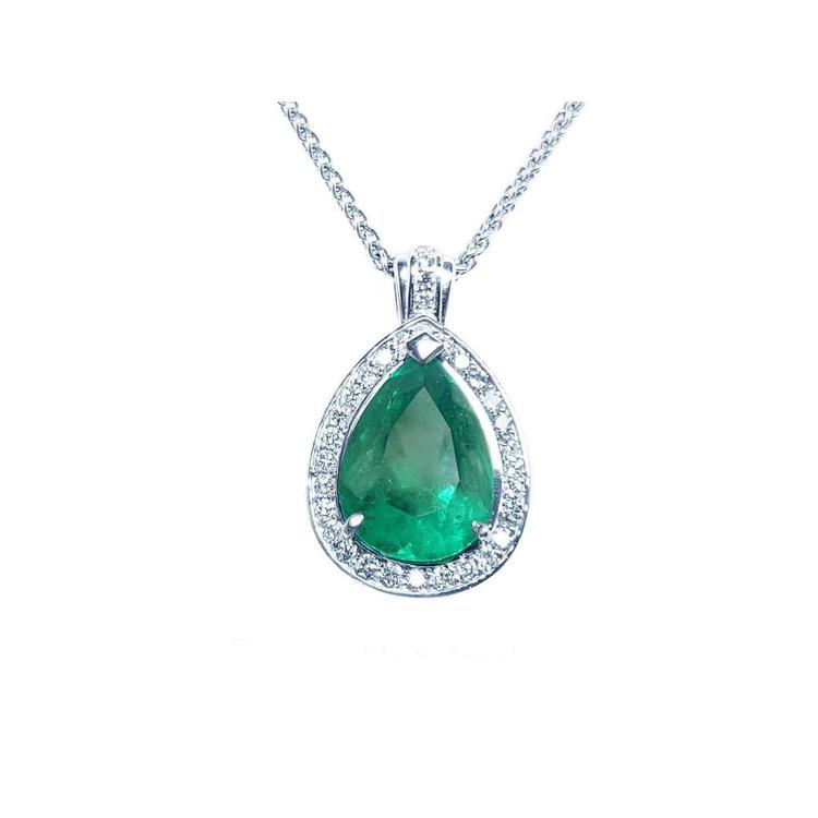 Emerald teardrop pendant with diamond halo on a topside view.