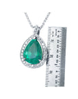 8.64 ct. pear-shaped emerald pendant with halo diamonds in 14K white gold, shown next to a metal ruler for scale.