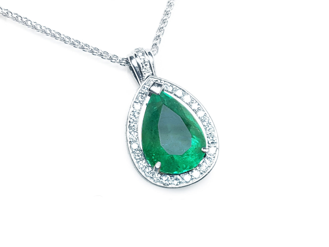 Teardrop-shaped emerald pendant with diamond accents on a topside view.