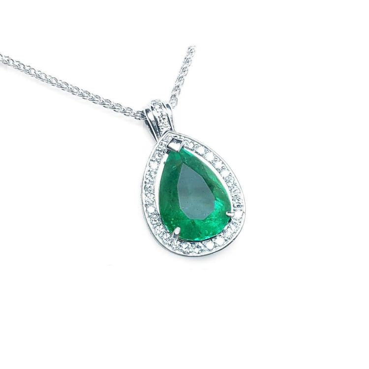 Teardrop-shaped emerald pendant with diamond accents on a topside view.
