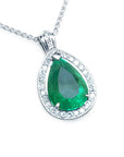 Teardrop-shaped emerald pendant with diamond accents on a topside view.