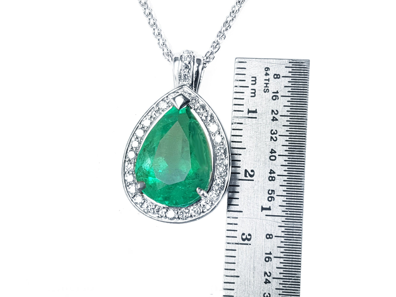 Emerald pendant with white gold chain next to a ruler for size reference