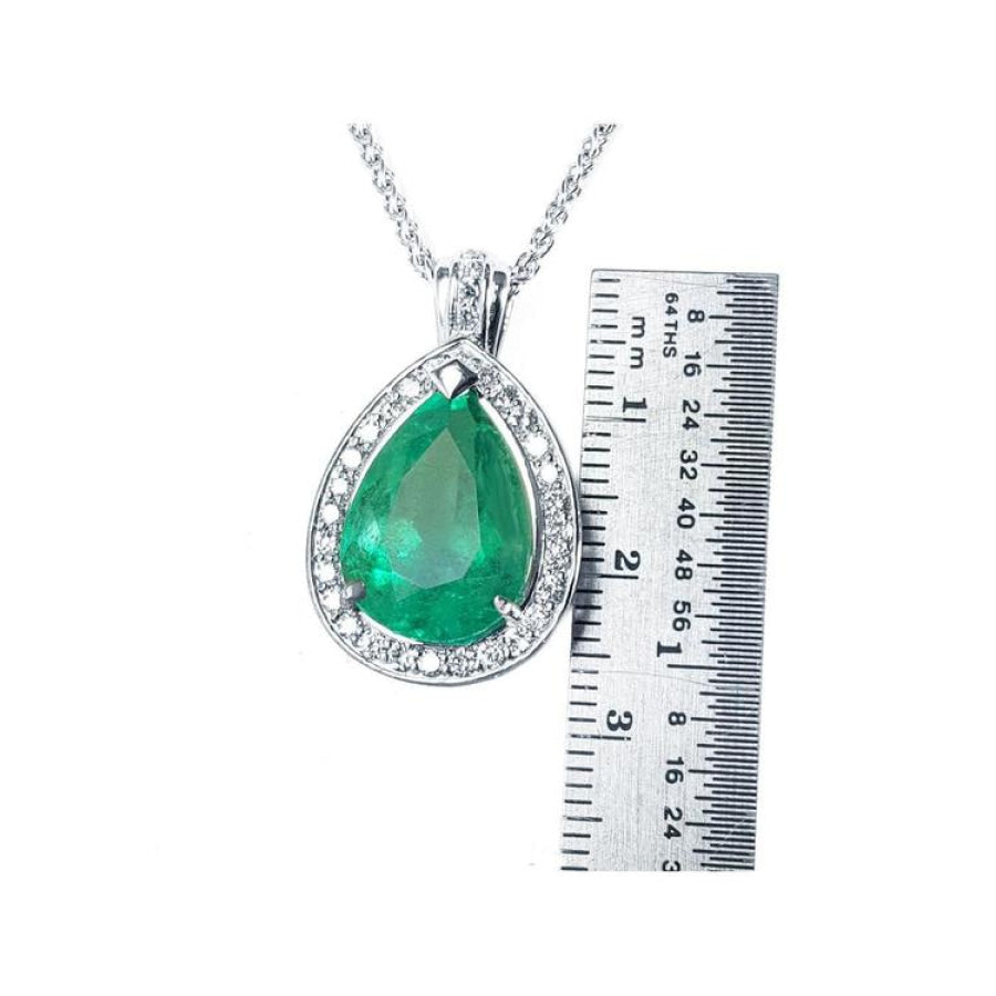 8.64 ct. pear-shaped emerald pendant with halo diamonds in 14K white gold, next to a ruler.