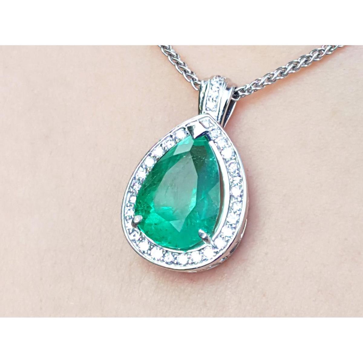 Green emerald pendant with white gold chain on beige skin background