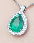 Green emerald pendant with white gold chain on beige skin background