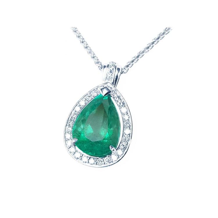Emerald green teardrop pendant with diamond halo on a left side position topside visible.