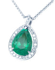 Emerald green teardrop pendant with diamond halo on a left side position topside visible.
