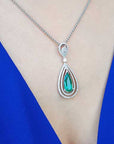 Teardrop-shaped emerald pendant on a white gold chain on a person's chest