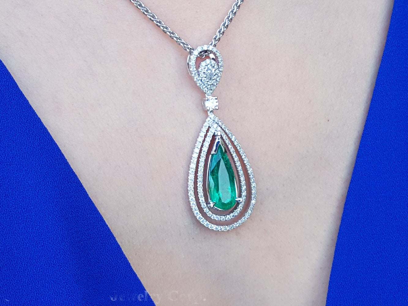 Emerald pendant necklace on a person wearing a blue dress