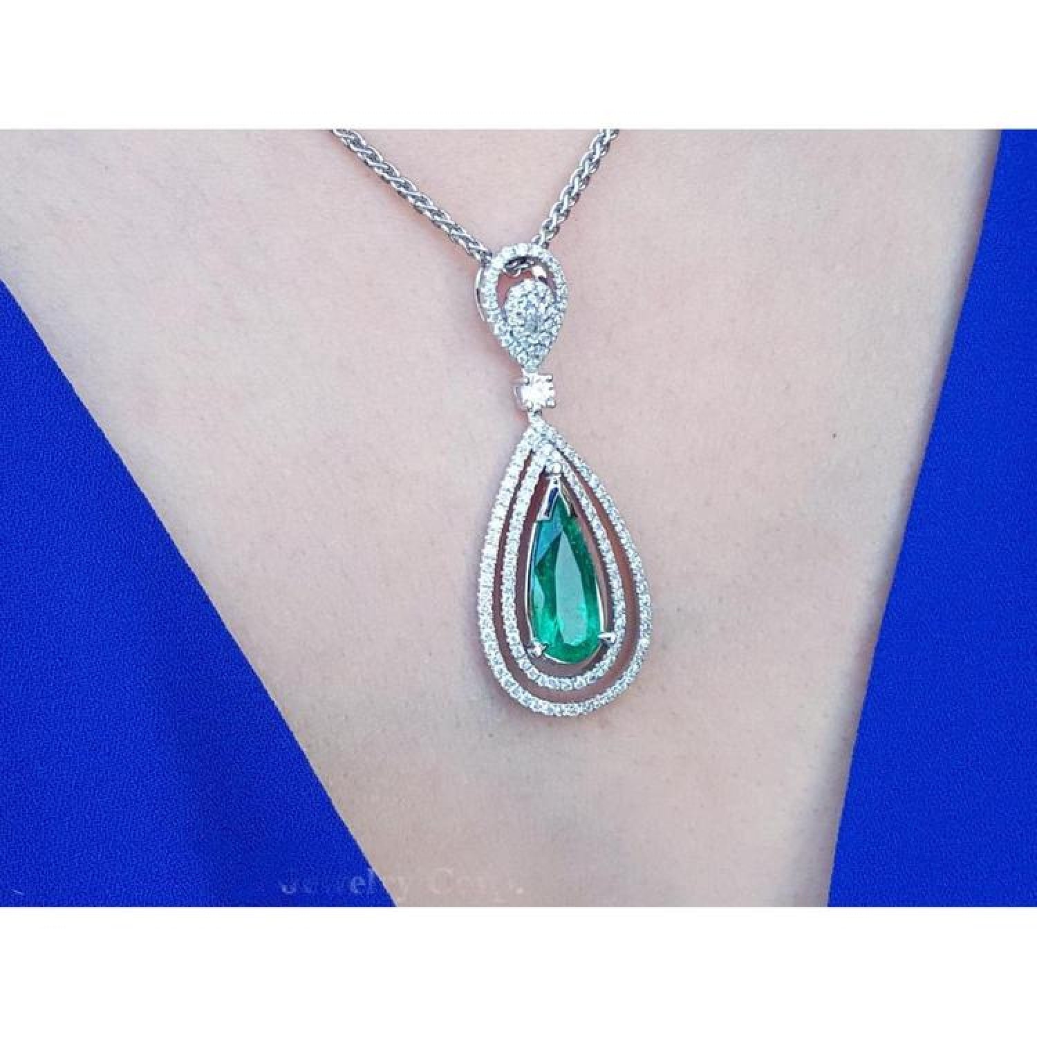 2.13 ct teardrop emerald pendant with double diamond halo, set in 18K white gold on a woman's neck.