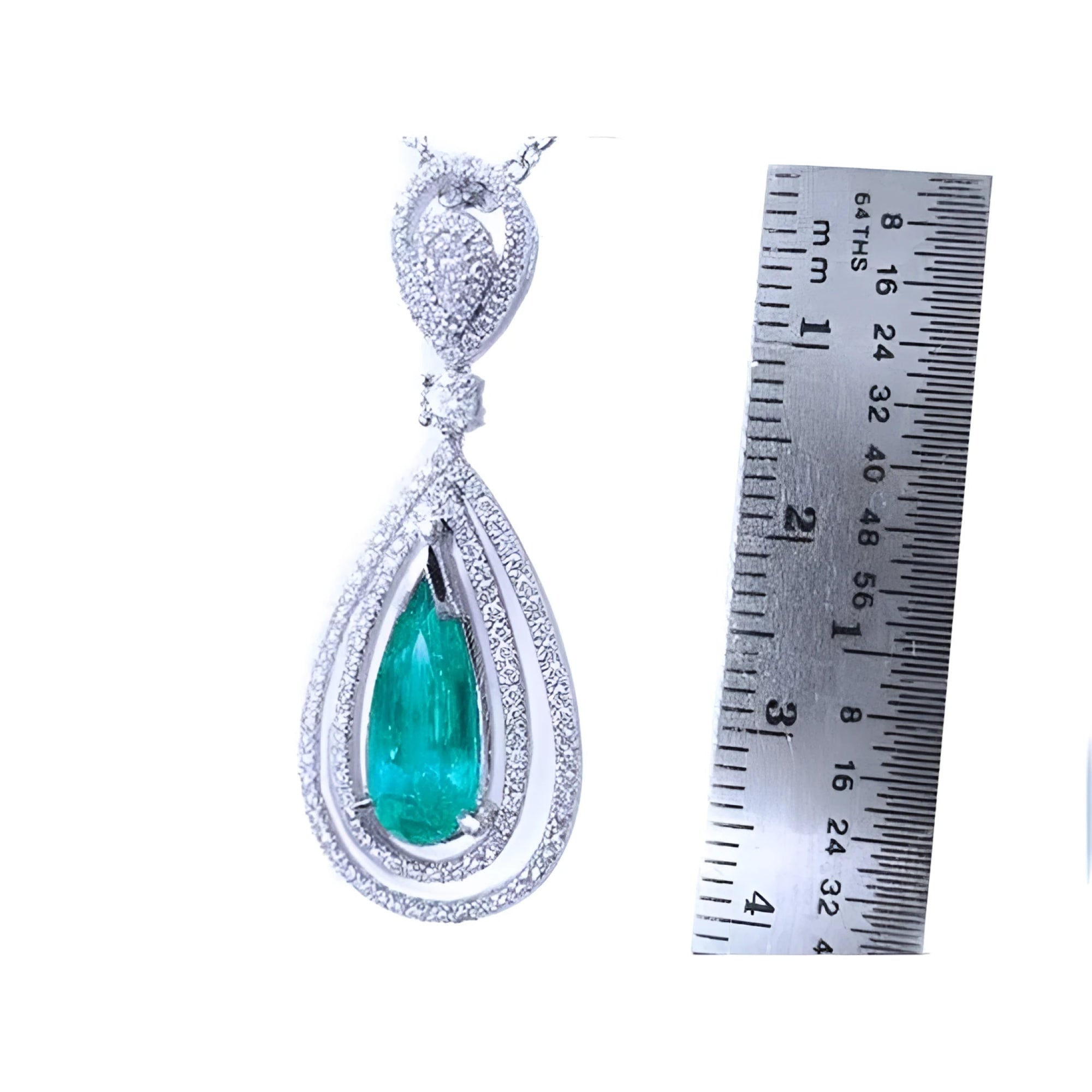 2.13 ct teardrop emerald pendant with double diamond halo in 18K white gold, next to a ruler.
