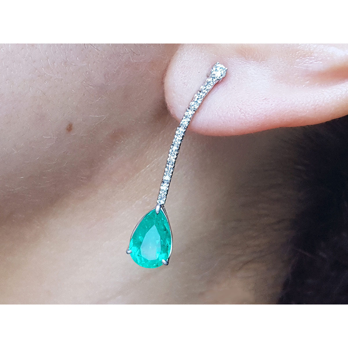 Teardrop emerald green gemstone earring on a person&#39;s ear