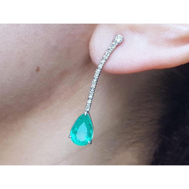 Teardrop emerald green gemstone earring on a person's ear
