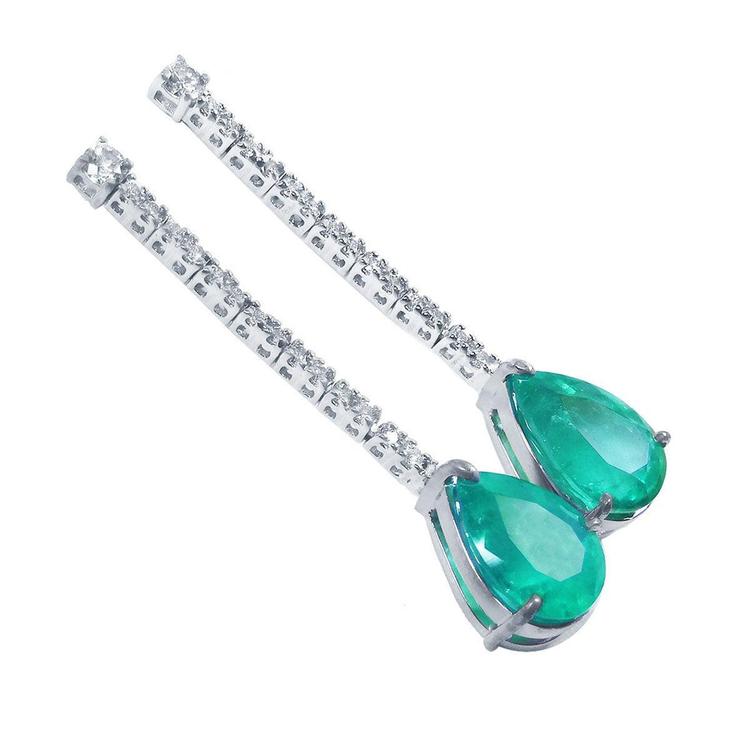 Pair of teardrop natural emerald earrings and diamond-studded clasps on a white background