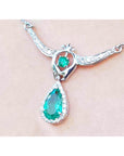 Pear shaped emerald necklace with diamond halo and round emerald accent in 14K white gold.