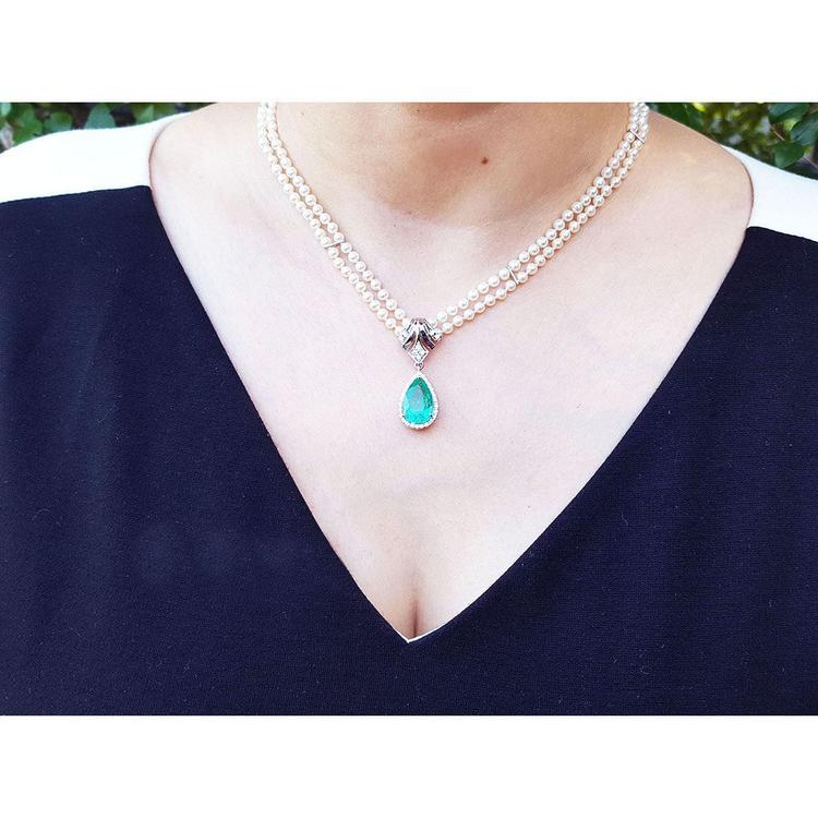 Pear emerald enhancer necklace with halo diamonds on a double strand pearl chain.