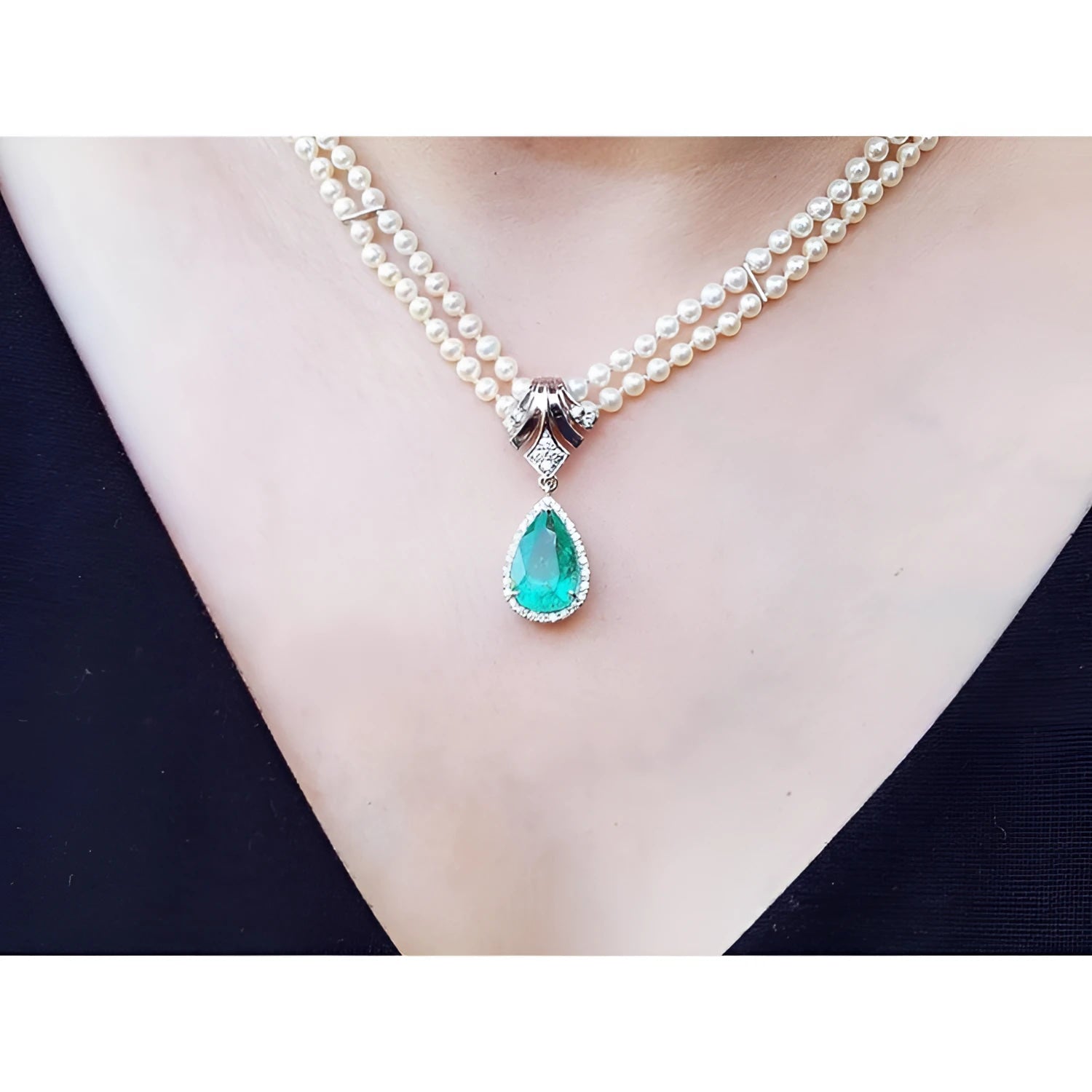 Pear-shaped emerald enhancer necklace with halo diamonds, dangling from a double strand pearl necklace.