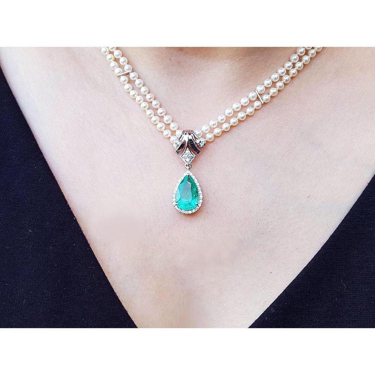 Pear-shaped emerald enhancer necklace with halo diamonds, dangling from a double strand pearl necklace.