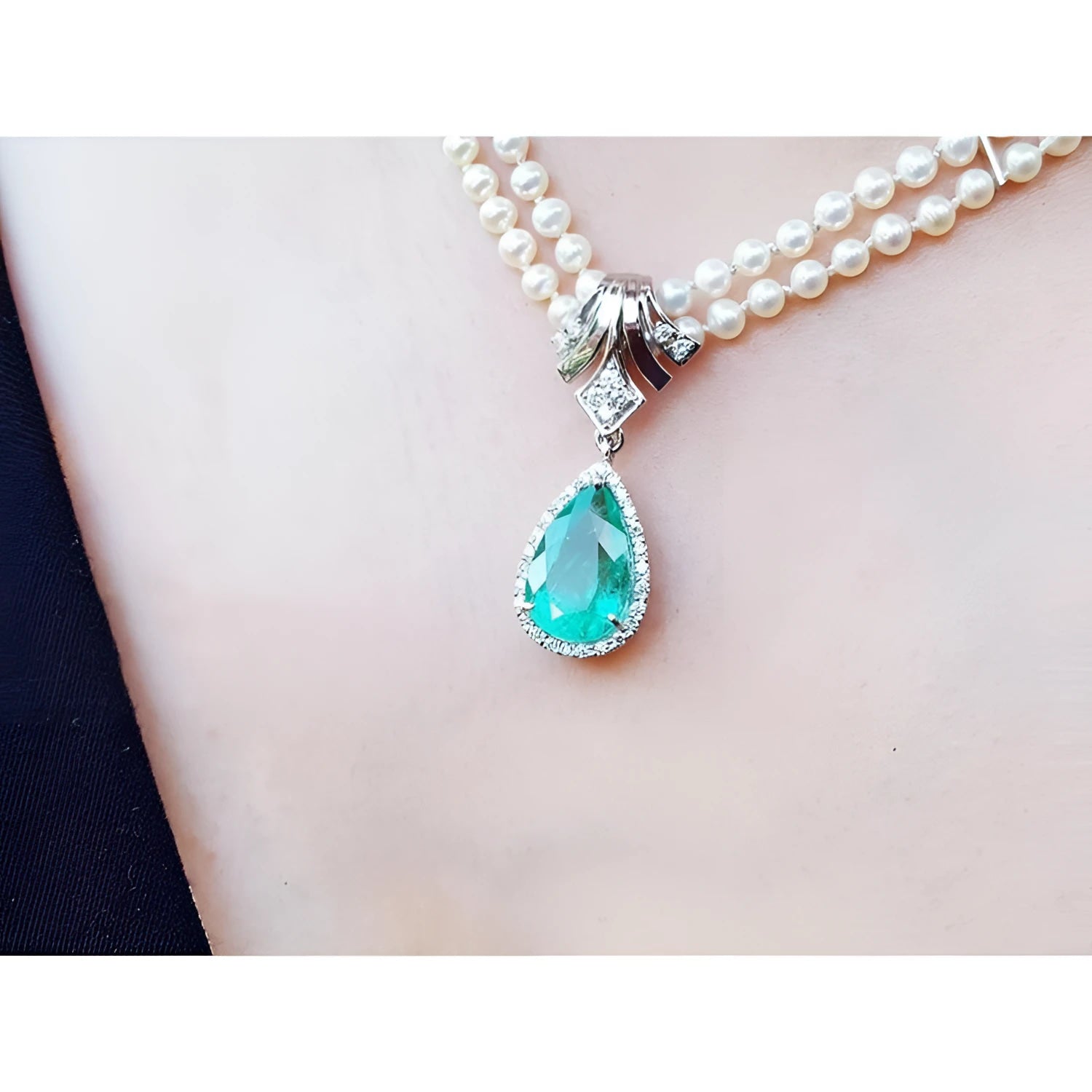Pear-shaped emerald enhancer necklace with halo diamonds on a double strand pearl chain.