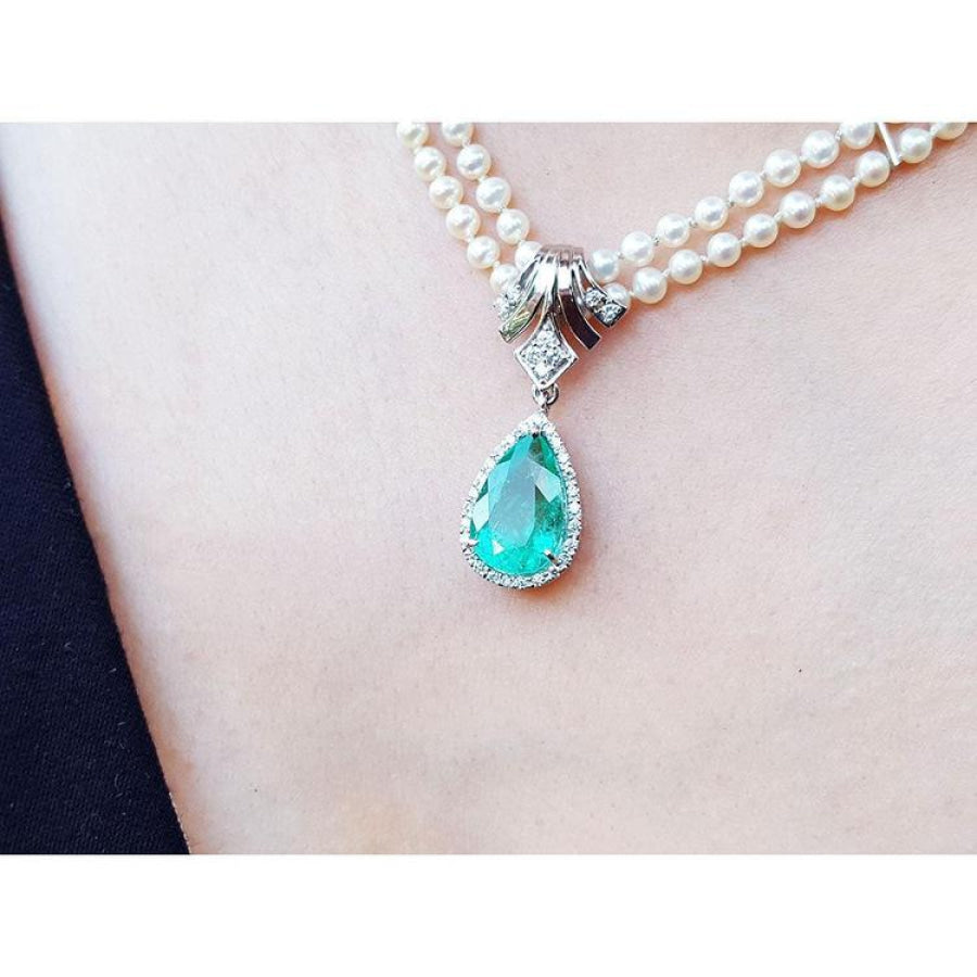 Pear-shaped emerald enhancer necklace with halo diamonds on a double strand pearl chain.