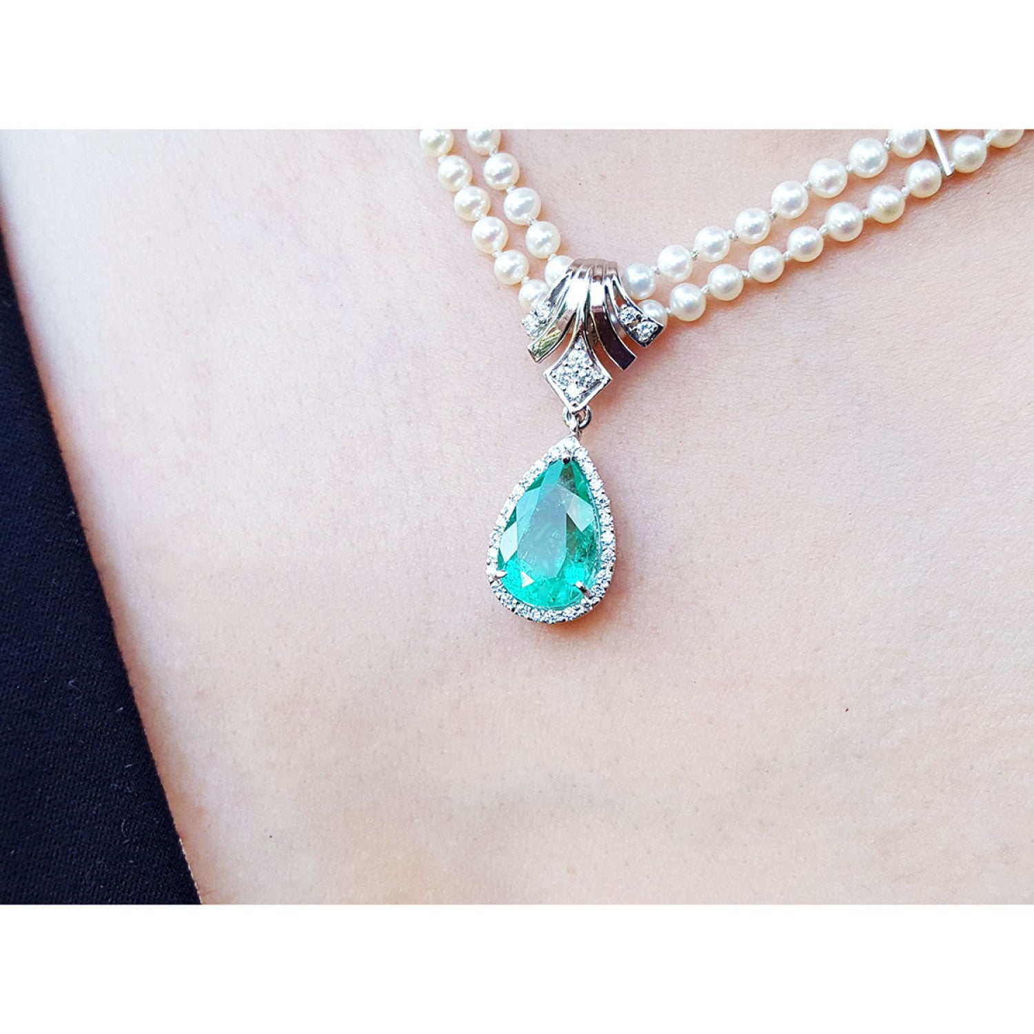 Pear-shaped emerald enhancer necklace with halo diamonds on a double strand pearl chain.
