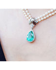 Pear-shaped emerald enhancer necklace with halo diamonds on a double strand pearl chain.