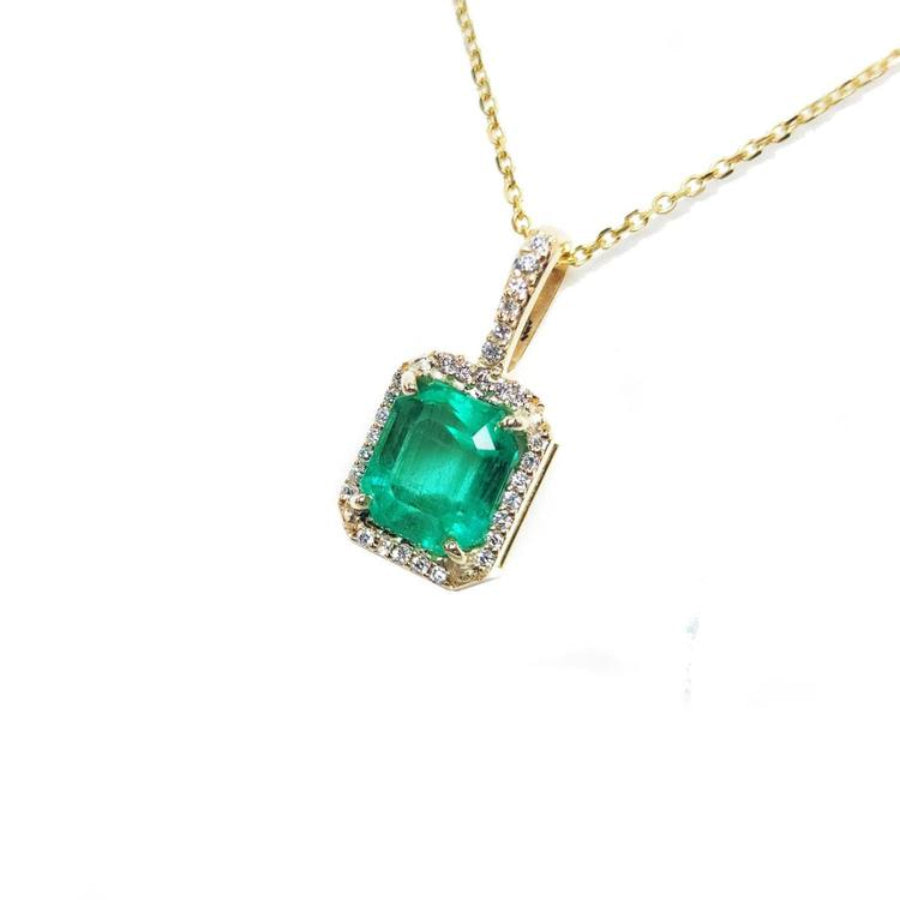 Emerald-cut emerald pendant with diamond halo on a 14k yellow gold chain.