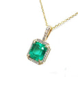 Emerald-cut emerald pendant with diamond halo on a 14k yellow gold chain.