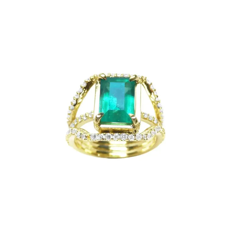 En posición frontal alta este anillo muestra una esmeralda rectangular sostenida sobre tres líneas de diamantes.