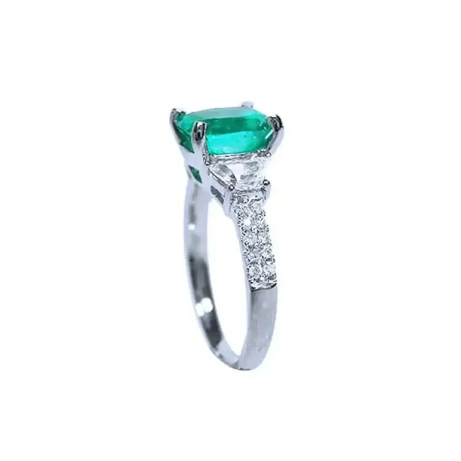Anillo de compromiso de oro blanco 18k con esmeralda colombiana ovalada y diamantes trapezoide.