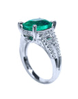 Esmeralda corte cojín y diamantes en anillo de compromiso en oro blanco, mostrando flanco izquierdo.