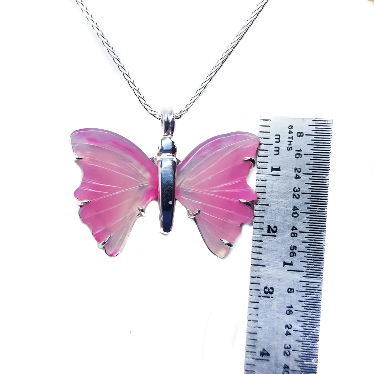 Pink natural agate butterfly pendant with silver setting on a silver chain, next to a ruler.