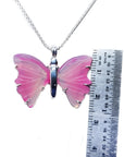 Pink natural agate butterfly pendant with silver setting on a silver chain, next to a ruler.