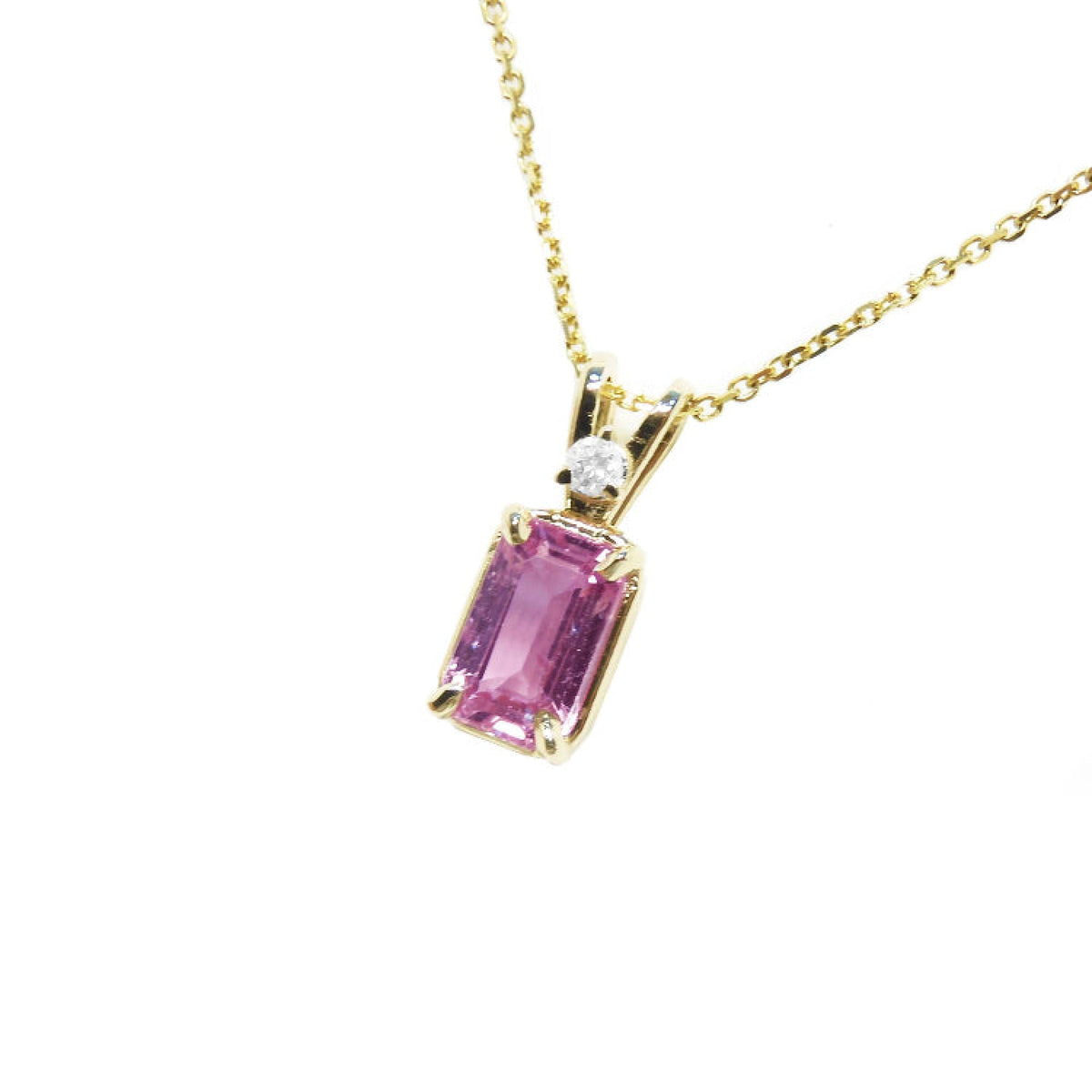 Genuine emerald cut pink sapphire and diamond pendant in 14k gold.