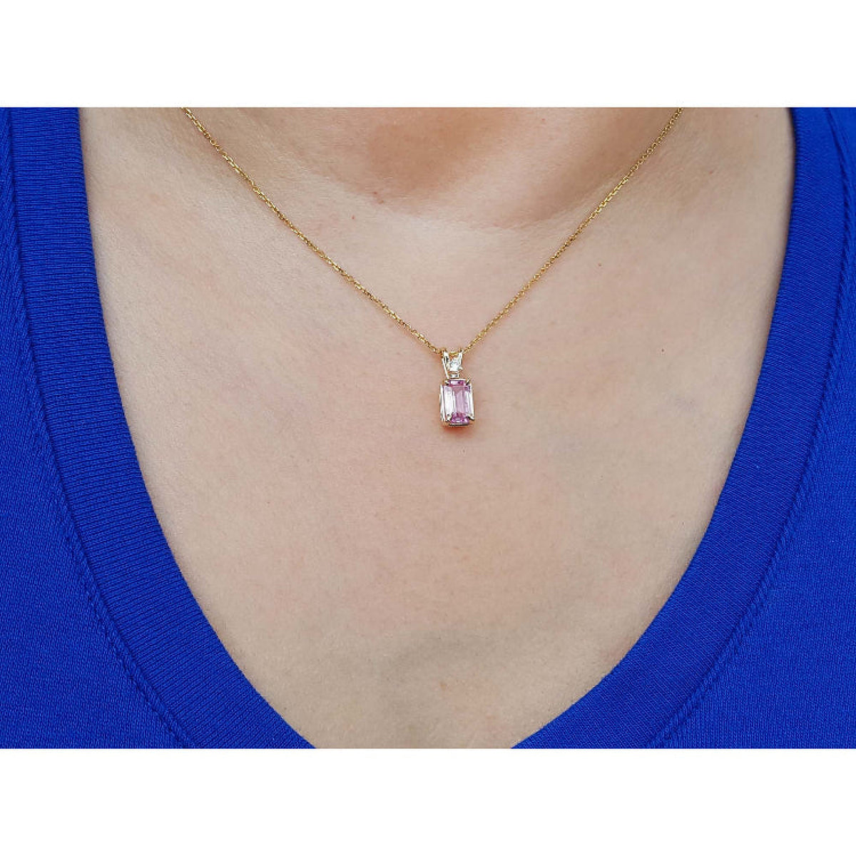 14k gold necklace with a pink genuine sapphire pendant worn by a person in a blue top.